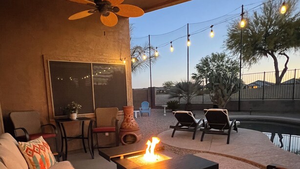 An outdoor patio area with a fire feature, seating, and string lights. - Golfer's Paradise!!!-On Johnson Ranch Golf Course with pool! (San Tan Valley)