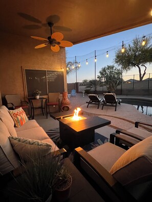 An outdoor patio area with a fire feature, seating, and string lights. - Golfer's Paradise!!!-On Johnson Ranch Golf Course with pool! (San Tan Valley)
