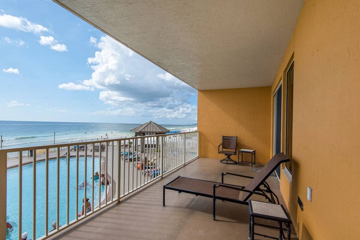 A balcony with a view of the beach and pool.