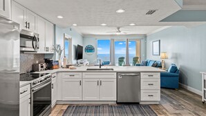 A modern kitchen with white cabinets, stainless steel appliances, and a large island.