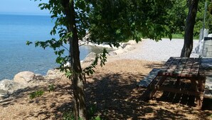 Eine hölzerne Bank und ein Picknicktisch an einer felsigen Küstenlinie mit freiem Blick auf das Meer.