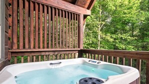 Un jacuzzi en una terraza de madera con vistas a un bosque.
