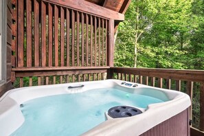 Un bain à remous sur une terrasse en bois, avec vue sur une forêt.