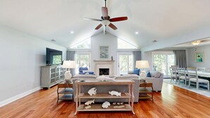 A spacious living room with a high ceiling, a fireplace, a dining area, and a television. - Stunning Hilton Head Island Vacation Rental! (Hilton Head)
