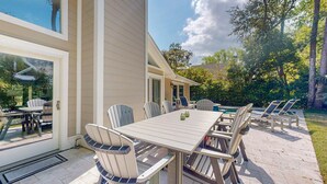 An outdoor patio with a table and chairs, a pool, and a view of the surrounding greenery. - Stunning Hilton Head Island Vacation Rental! (Hilton Head)