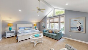 A bedroom with a bed, a nightstand, a side table, a sofa, and a ceiling fan. - Stunning Hilton Head Island Vacation Rental! (Hilton Head)