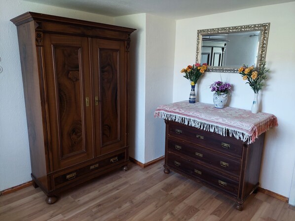 A wooden wardrobe with multiple drawers and a mirror above it.