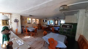 Un espace repas avec plusieurs tables et chaises, un comptoir avec une caisse enregistreuse et un meuble vert.