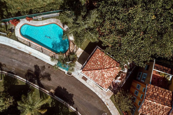 An aerial view of a property with a swimming pool, a paved area, and a building with a tiled roof. - Landing View 206 with private rooftop terrace (Rincón)