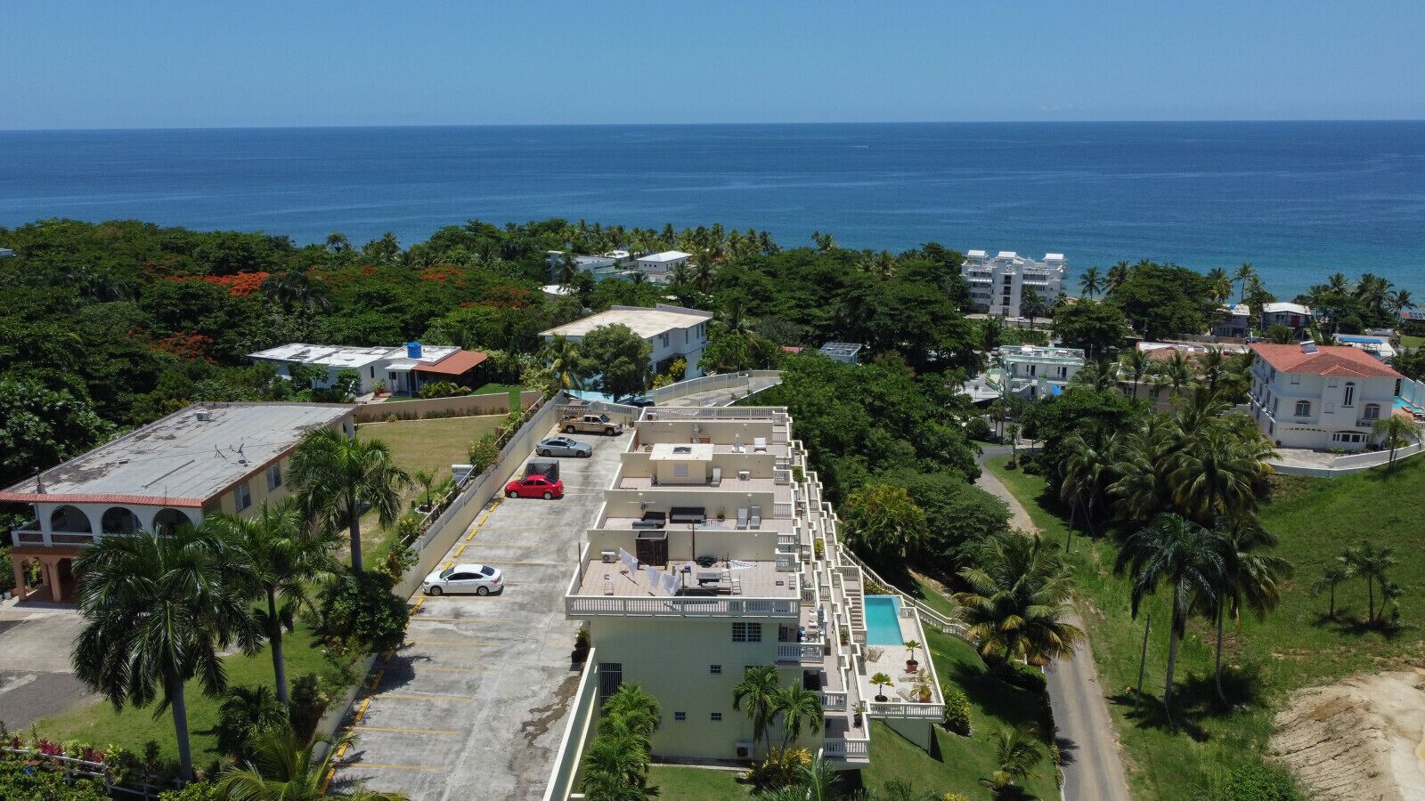 A coastal hotel with multiple buildings, a swimming pool, and a view of the ocean.