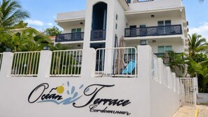 A white building with balconies and a sign that reads "Ocean Terrace Condominium". - Ocean Terrace 202 a 4 min walk to Sandy Beach (Rincon)