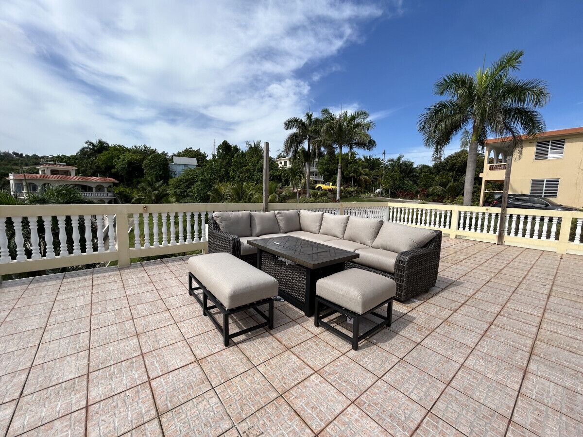 Une terrasse avec un canapé d’angle, deux poufs et une petite table.