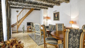 A dining area with a wooden table and patterned chairs, a staircase, and a framed picture on the wall. - Maisonette 2 bedroom Apartment in the Heart of Prague (Prague)
