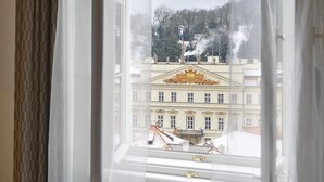 A room with a bed, a window with sheer curtains, and a view of a building with a golden facade. - Maisonette 2 bedroom Apartment in the Heart of Prague (Prague)