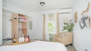 Un dormitorio con cama, armario de madera, sillón colgante y planta.