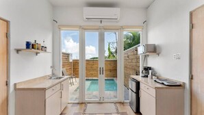 Une cuisine compacte avec vue sur une piscine, un climatiseur intégré et un petit coin café.