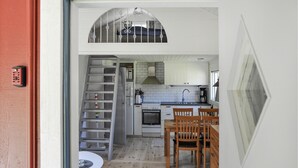 A compact kitchen with a central island, a dining area with wooden chairs, and a staircase leading to an upper level. - Pet friendly home in Stillingsön (Stillingsön)