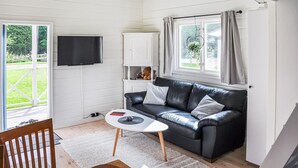 A cozy living room with a black leather sofa, a white coffee table, and a TV mounted on the wall. - Pet friendly home in Stillingsön (Stillingsön)