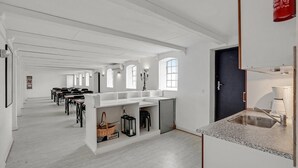 A spacious room with a long table and chairs, a kitchen area with a sink, and a dark door. - Amazing home in Søllested with WiFi (Søllested)