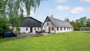 A rustic building with a large barn and a smaller house, both with white walls and dark roofs, set in a grassy area with a soccer goal visible. - Amazing home in Søllested with WiFi (Søllested)
