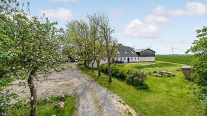 A rural property with a gravel path leading to a white building with a sloped roof, surrounded by green fields and trees. - Amazing home in Søllested with WiFi (Søllested)