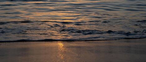 Un tramonto sul mare calmo, con onde leggere.