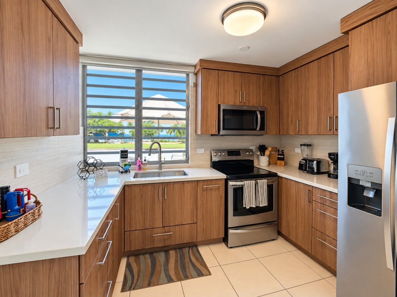 A modern kitchen with wooden cabinets, stainless steel appliances, and a large window offering a view of the outdoors.