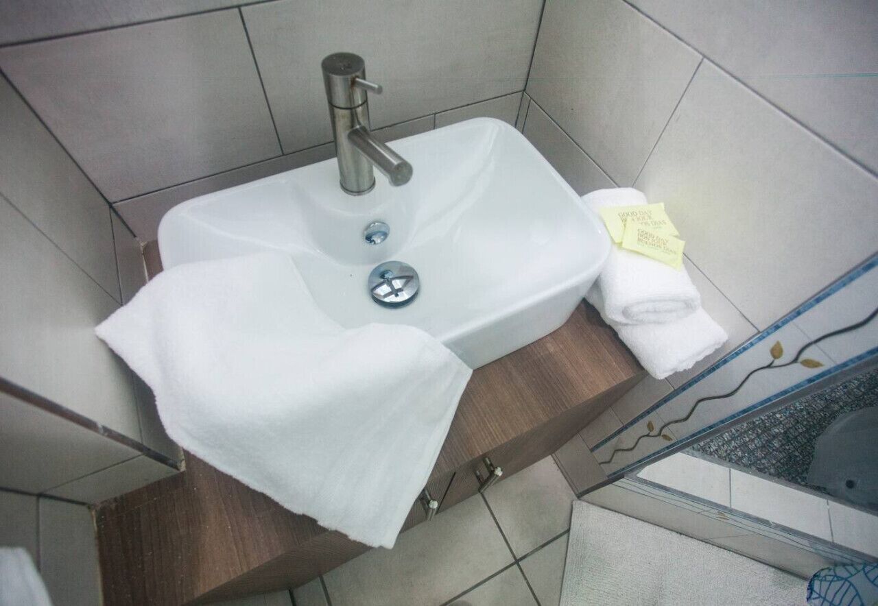 A bathroom with a white sink, a towel, and a glass shower enclosure.