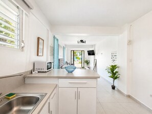 A modern kitchen with a central island, a microwave, and a sink. - Aguada Beachfront Studio | 5 Min to Rincon (Aguada)
