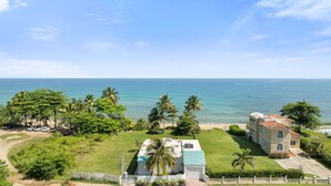 Una propiedad frente a la playa con una casa grande, una piscina y vistas al océano.