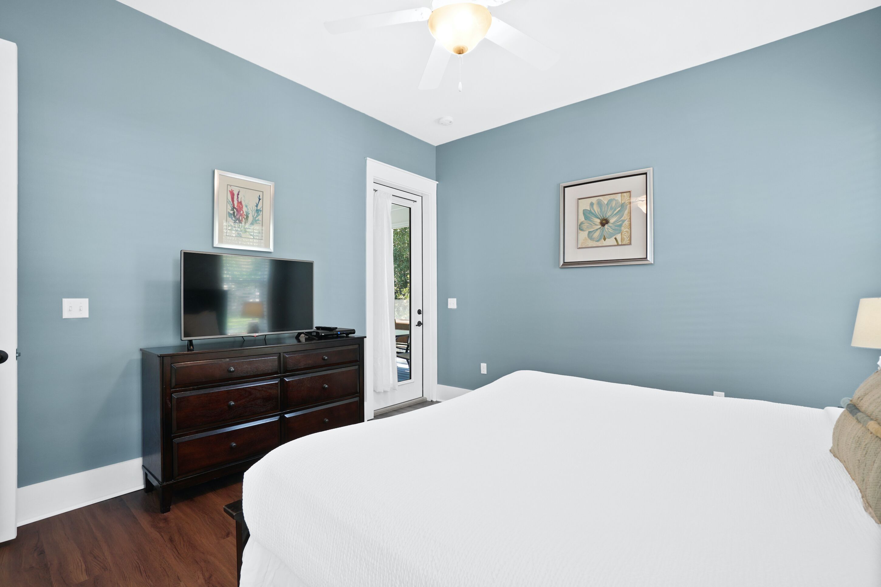 A bedroom with a bed, a dresser, a television, and two framed pictures on the walls.