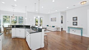 Une cuisine moderne avec des meubles blancs, un plan de travail noir et des luminaires suspendus.