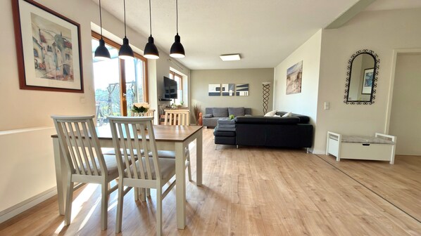 A modern living space with a dining area, sofa, and a small bed.