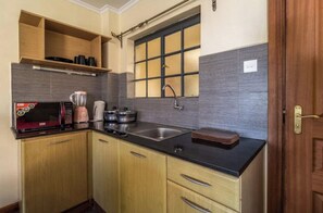 Cocina compacta con microondas, cafetera y pileta.