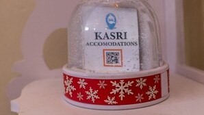 A snow globe with a label reading "KASRI ACCOMODATIONS" and a QR code.