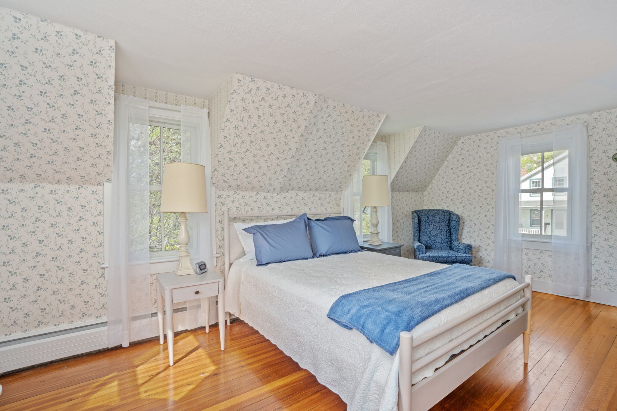 A bedroom with a bed, two bedside tables, a chair, and a window.