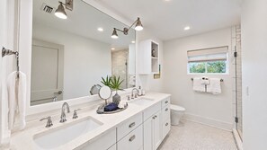 A modern bathroom with a double sink, a large mirror, and a shower area.