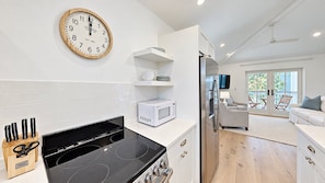 A modern kitchen with a built-in stove, microwave, and a clock on the wall. - Crystal Blue Persuasion - 1BR/1BA Blue Mountain Beach Carriage House - Sleeps 2 (Santa Rosa Beach)