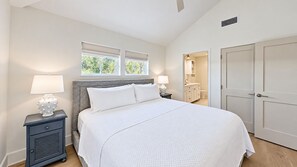 A bedroom with a bed, bedside tables, a window, a door, and a bathroom visible through an open door. - Crystal Blue Persuasion - 1BR/1BA Blue Mountain Beach Carriage House - Sleeps 2 (Santa Rosa Beach)