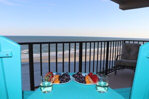 A balcony with a table set for two, overlooking a beach. - OCEAN BLISS! Beautiful oceanfront condo with large balcony and amazing views! (North Myrtle Beach)