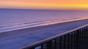 A beach with a railing, calm sea, and a sunset. -  OCEAN BLISS!  Beautiful oceanfront condo with large balcony and amazing views! (North Myrtle Beach)