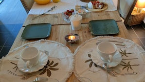 Een eettafel gedekt voor twee personen, met borden, bekers, bestek en een kaars.