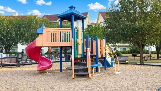 A playground with a slide, climbing structures, and a covered play area.