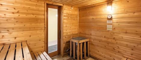 A sauna room with wooden walls, a bench, and a small table.
