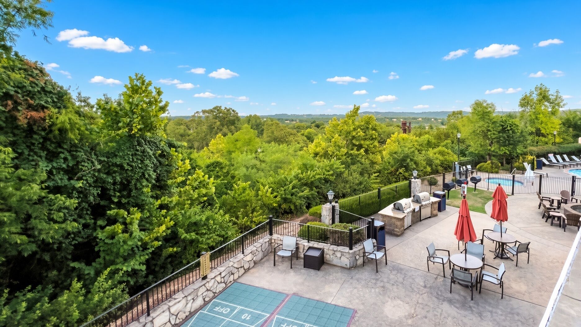 A rooftop patio with outdoor seating, a barbecue area, and a view of the surrounding greenery.