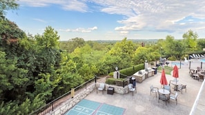 A rooftop patio with outdoor seating, a pool, and a scenic view of the surrounding forest.