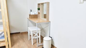 Ett litet, rent rum med ett skrivbord i trä, en vit stol och en papperskorg.
