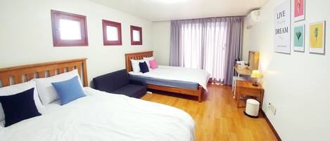 A hotel room with two beds, a desk, a chair, a nightstand, and a window with curtains.