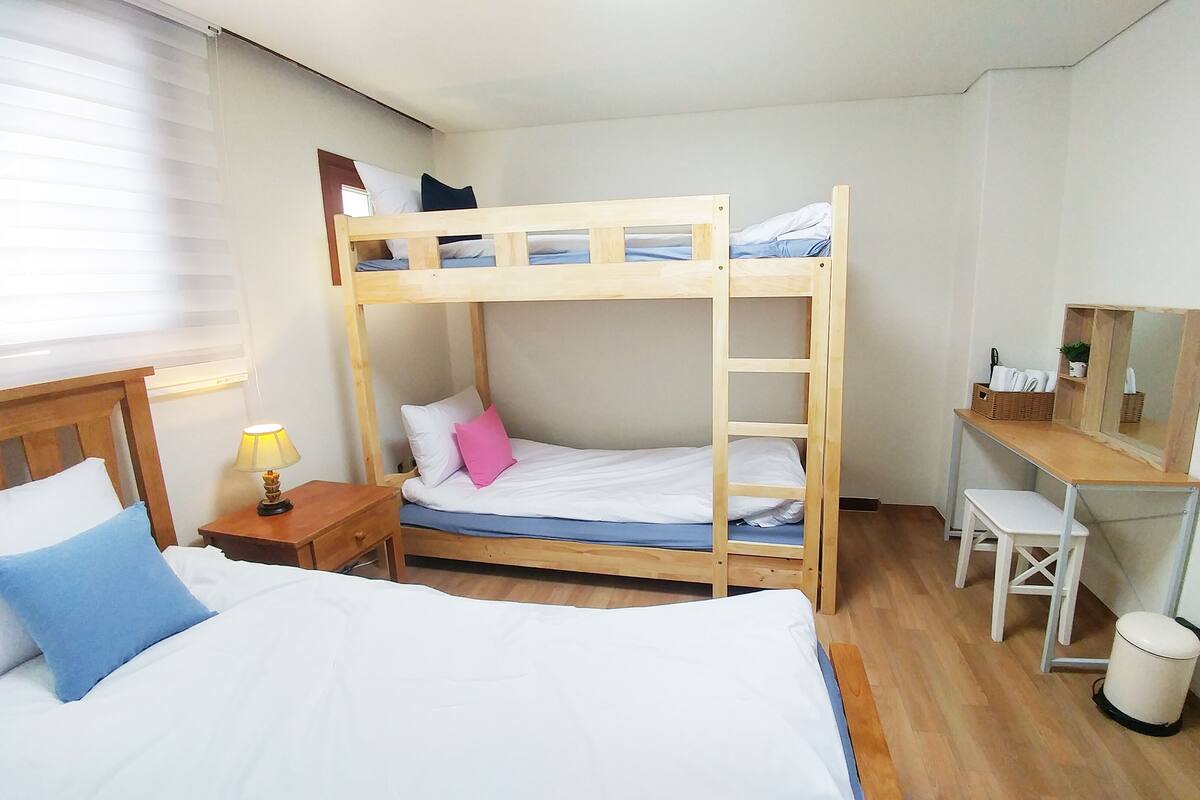 Quarto com beliche, escrivaninha, cadeira e lixeira pequena.
