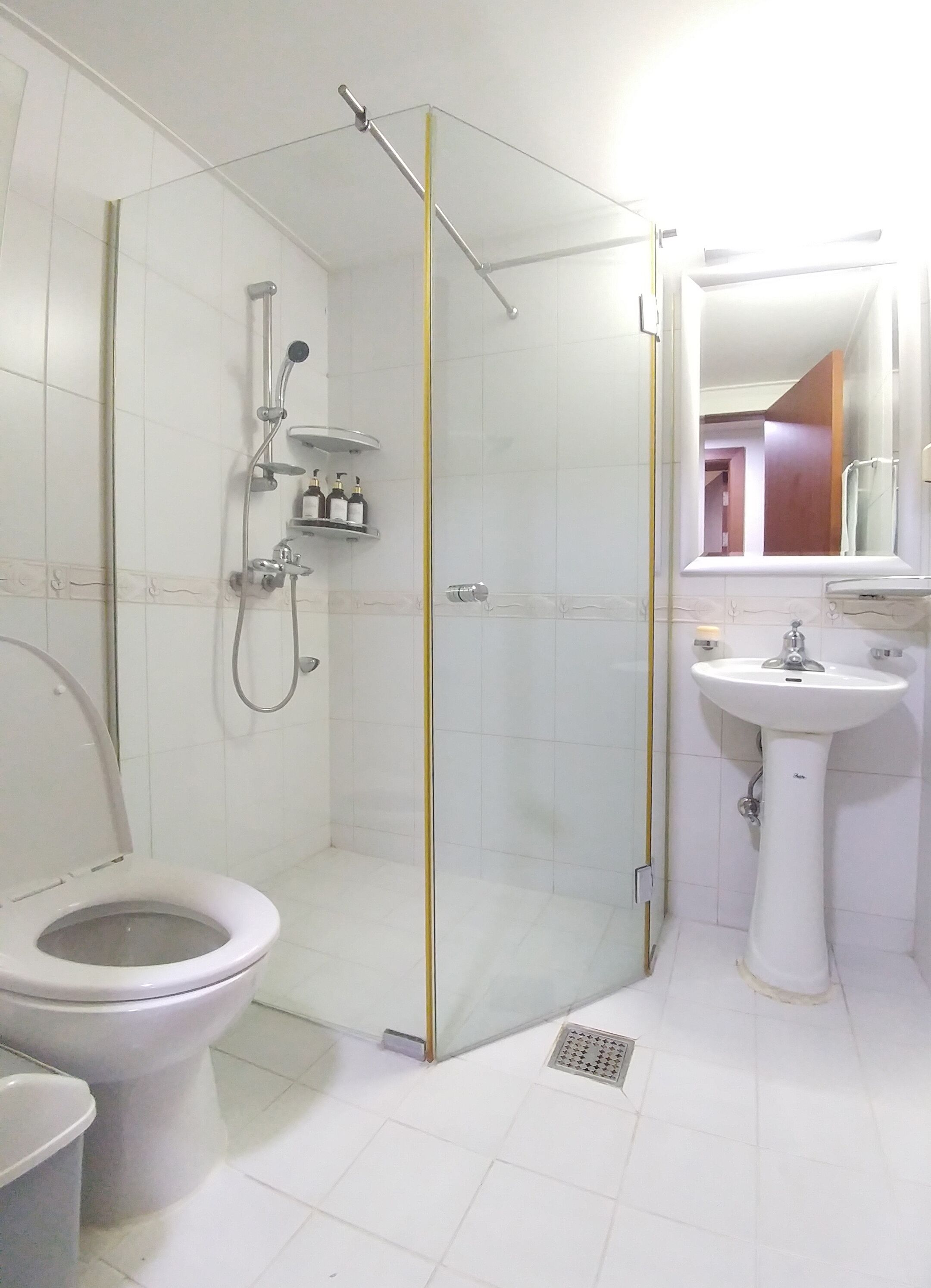 Un bany amb dutxa amb envà, vàter i un lavabo amb mirall a la part superior.